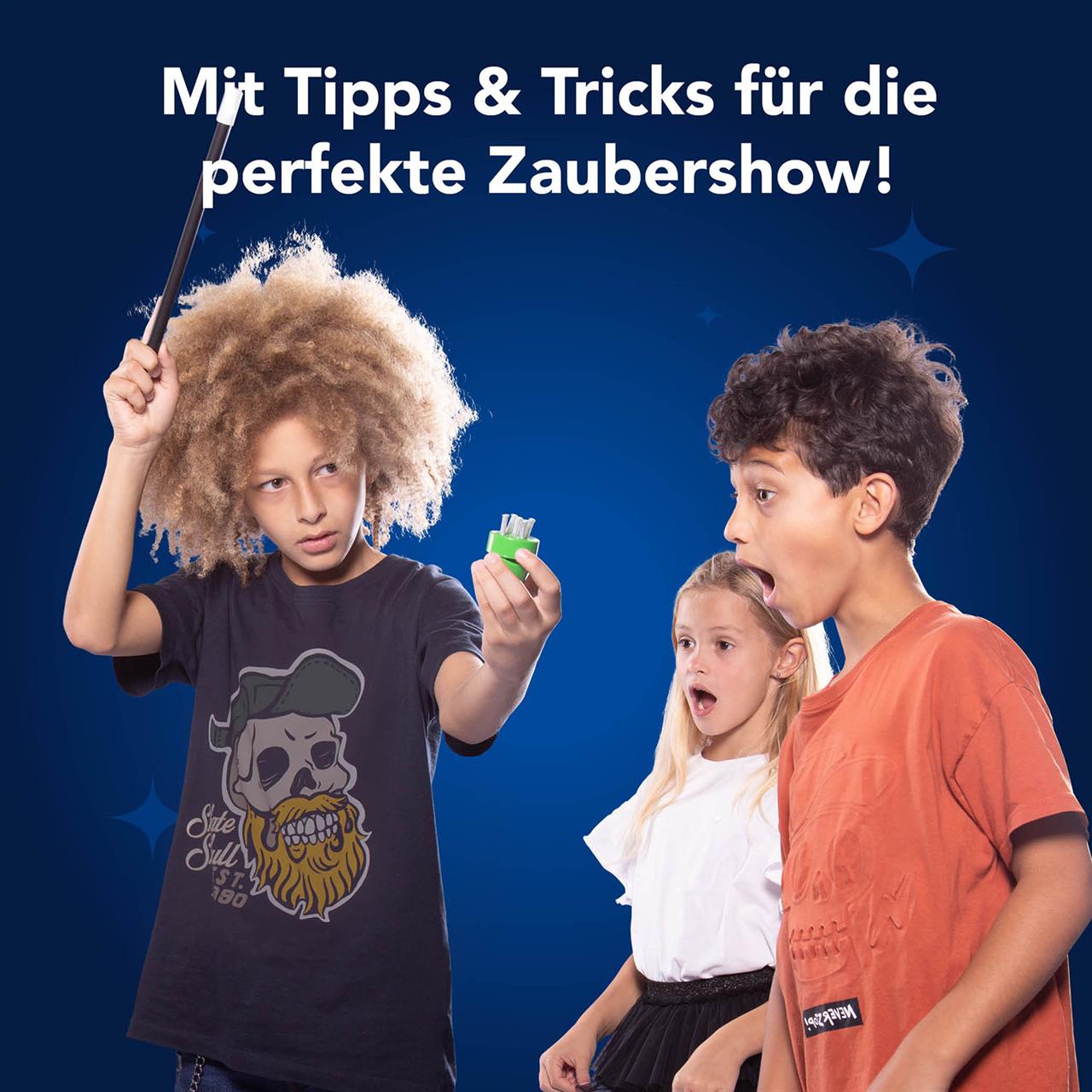 Ein Kind führt einen Zaubertrick mit einem Zauberstab und einem kleinen Requisit vor. Zwei andere Kinder schauen beeindruckt und erstaunt zu.