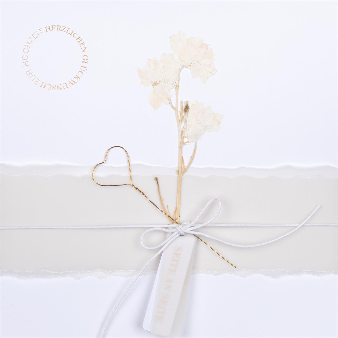 Die Karte zeigt ein elegantes Design mit getrockneten Blumen, einem goldenen Herz und einer weißen Schleife. Oben links steht im Kreis: "HERZLICHEN GLÜCKWUNSCH ZUR HOCHZEIT".