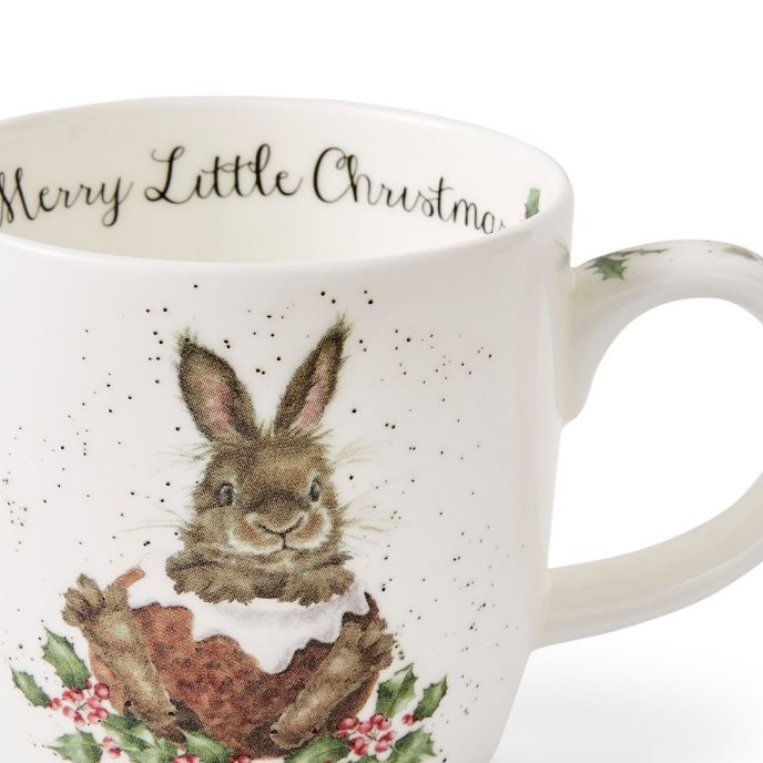 Auf der Tasse ist ein niedlicher Hase zu sehen, der in einer weihnachtlichen Szene sitzt. Am oberen Rand der Tasse steht der Schriftzug "Merry Little Christmas".
