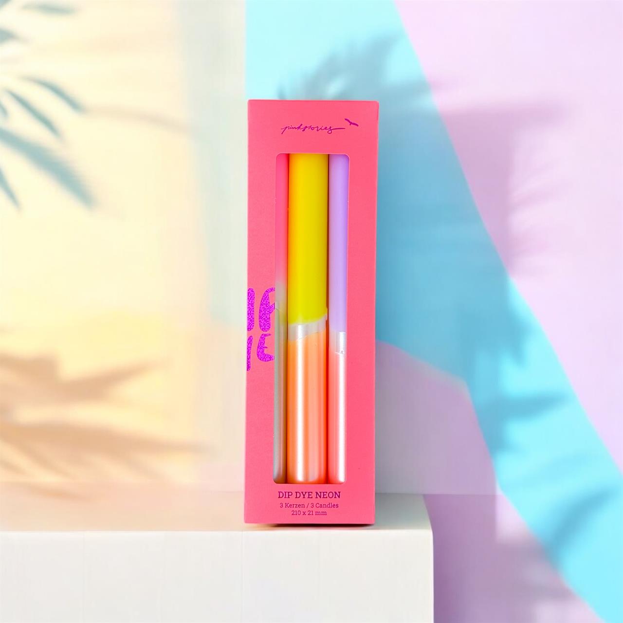 Die Abbildung zeigt das Produkt "Kerzen Dip Dye Neon 'Midsummer Sweets'" in einer pinken Verpackung. In der Schachtel befinden sich drei bunte, neonfarbene Kerzen.