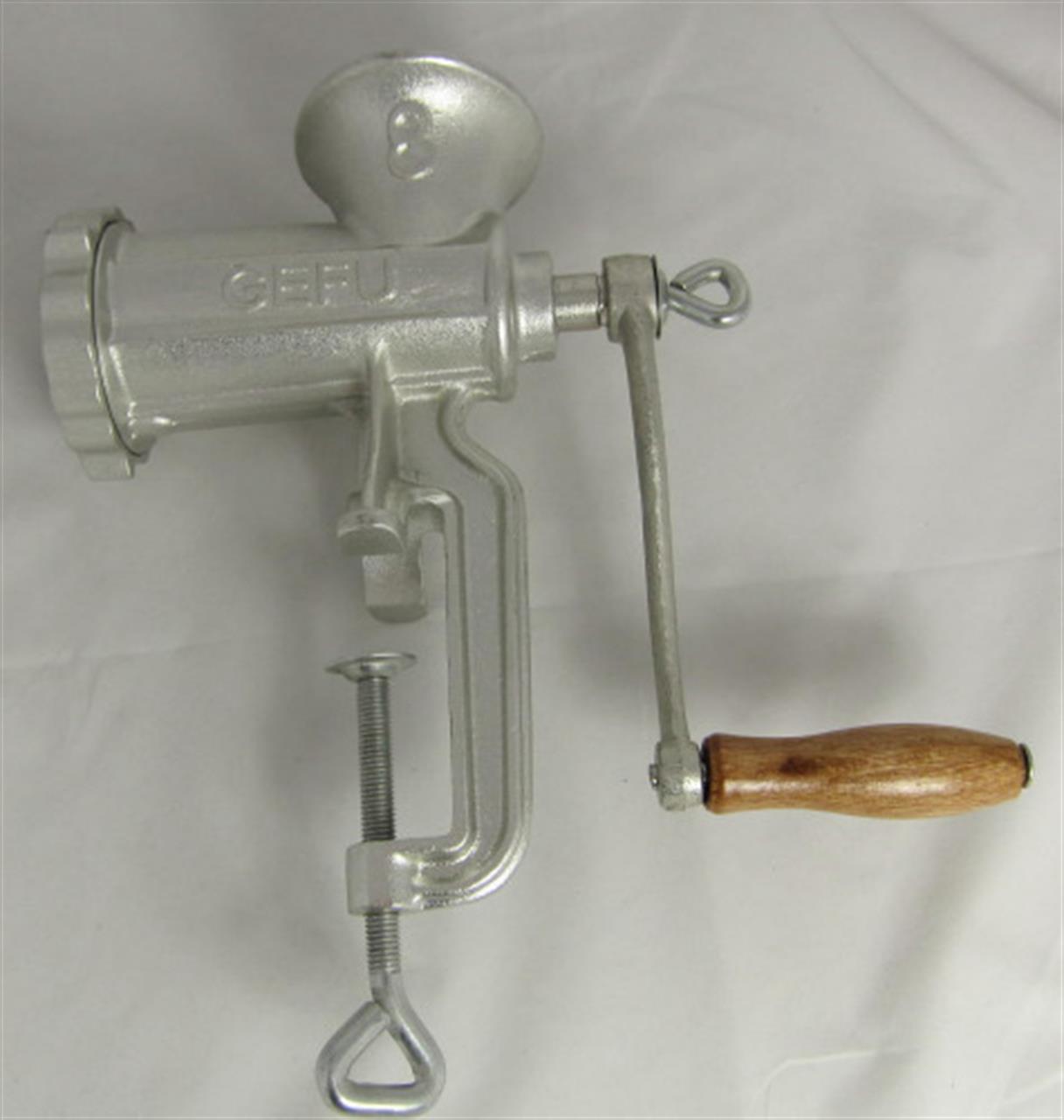 Auf dem Bild ist ein Fleischwolf aus Metall mit einer Holzkurbel zu sehen. Das Gerät heißt "Fleischwolf Trica Gr.7/8 inkl. Spritzgebäckvorsatz".