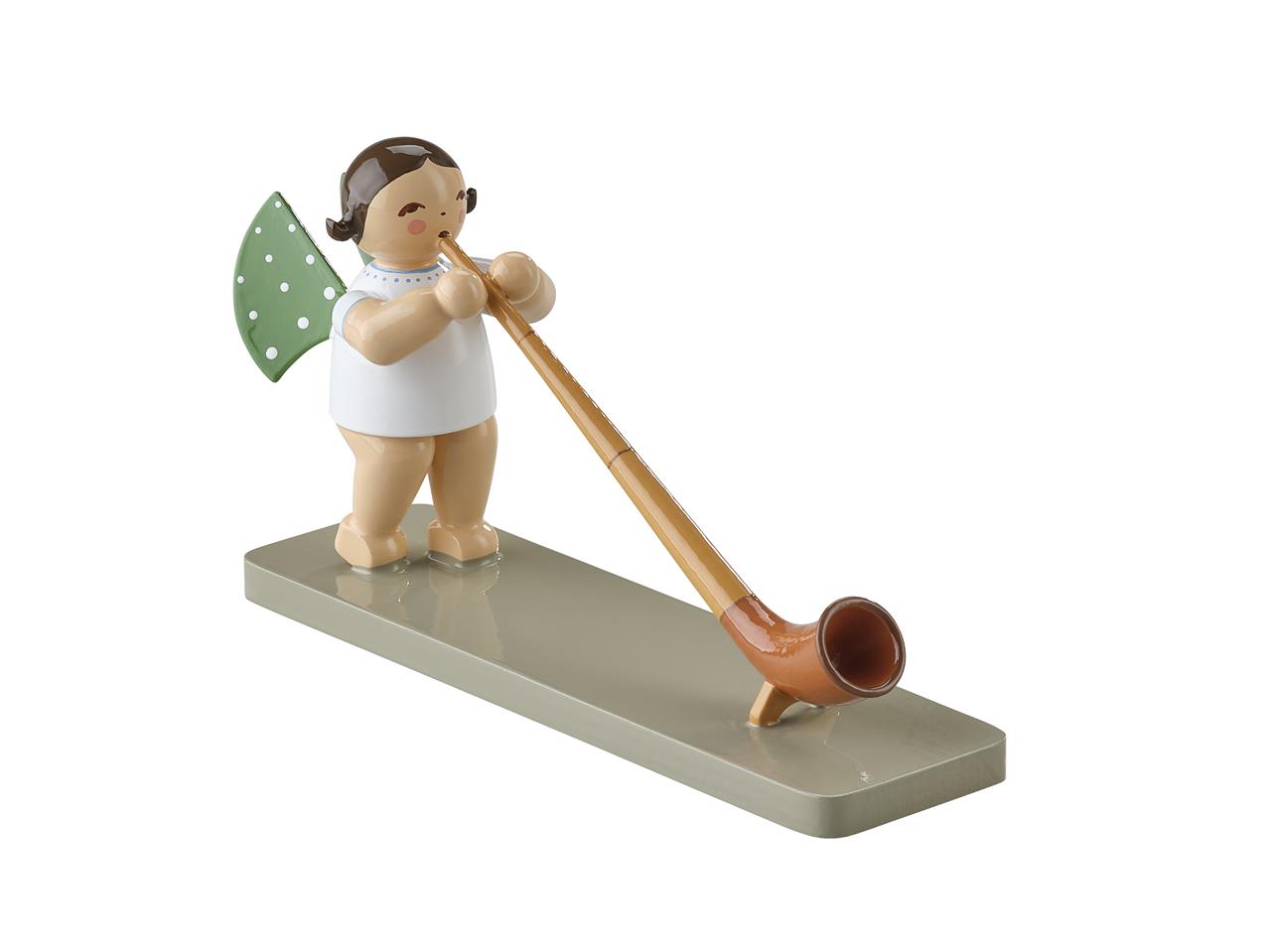 Die Abbildung zeigt eine kleine Engel-Figur mit grünen Flügeln und weißen Punkten, die ein Alphorn spielt. Die Figur steht auf einer rechteckigen, glatten Basis.