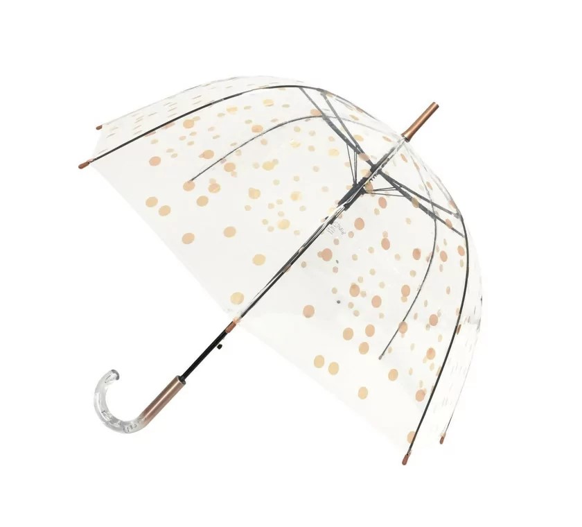 Der Schirm ist durchsichtig und hat ein Muster aus goldenen und kupferfarbenen Punkten. Er besitzt einen gebogenen Griff und einen eleganten Look.