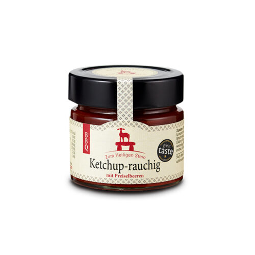 Das Bild zeigt ein Glas Ketchup-rauchig mit Preiselbeeren. Das Glas hat einen schwarzen Deckel und ein helles Etikett mit roter und schwarzer Schrift.