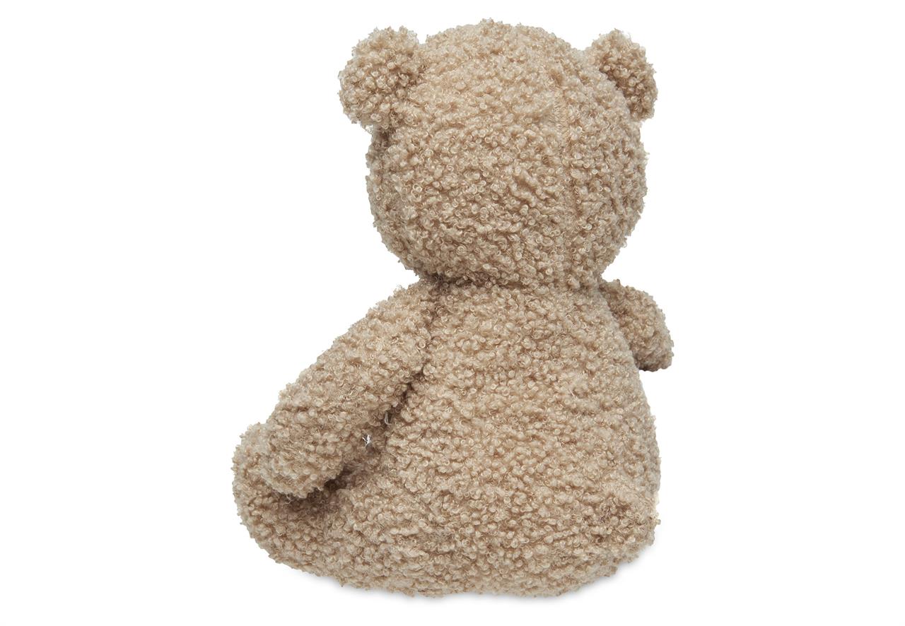 Das Bild zeigt ein Kuscheltier in Form eines Teddybären namens "Biscuit". Der Teddybär ist aus lockigem, beigem Plüsch und sitzt mit dem Rücken zur Kamera.