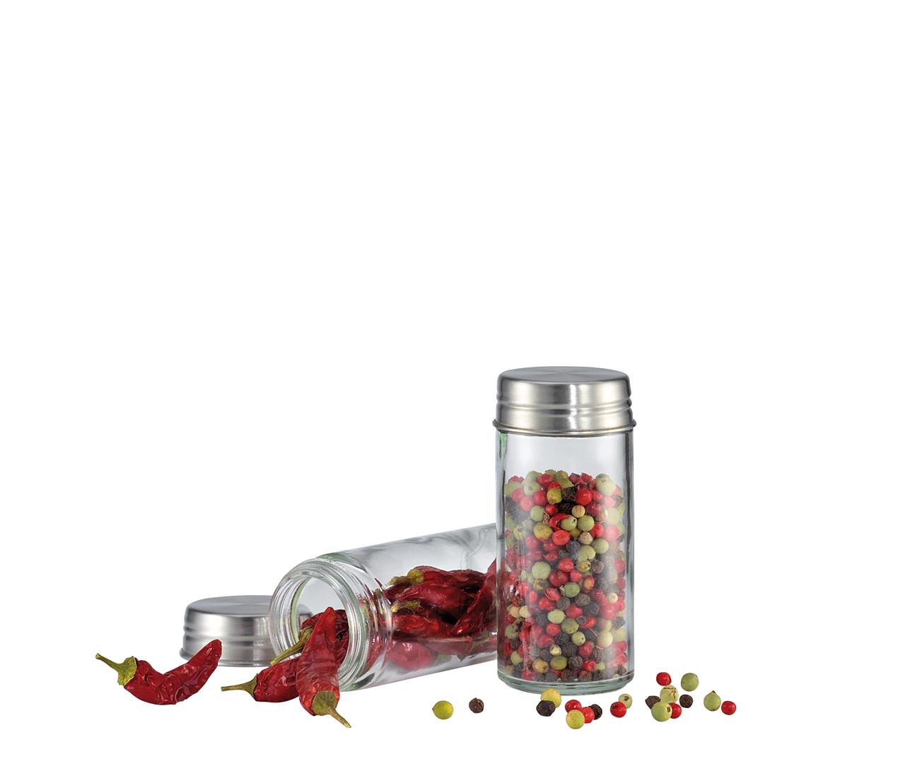 Auf dem Bild sind zwei Gewürzgläser aus Glas mit Deckeln aus Edelstahl zu sehen. In einem Glas sind bunte Pfefferkörner, im anderen getrocknete Chilischoten.