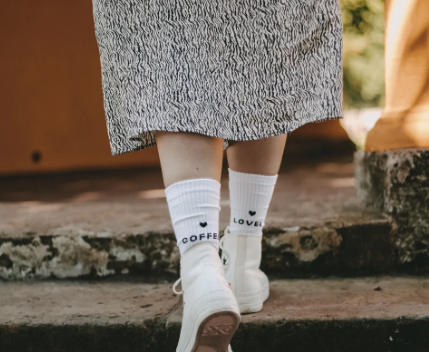 Das Bild zeigt ein Paar weiße Socken mit dem Aufdruck 'Coffee Lover' in Größe M. Die Socken sind für Kaffeeliebhaber gestaltet.