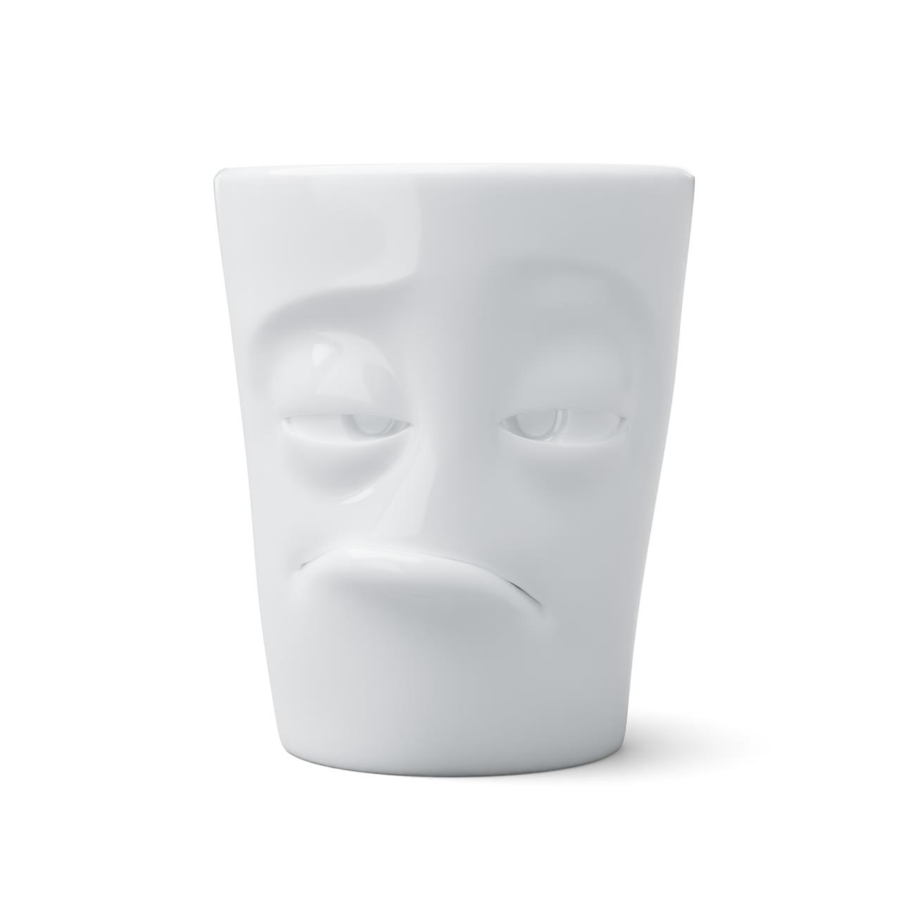 Die Tasse "Henkelbecher verpennt 350ml" zeigt ein verschlafenes Gesicht mit halb geschlossenen Augen und einem müden Ausdruck. Sie besteht aus weißer Keramik und fasst 350 ml.