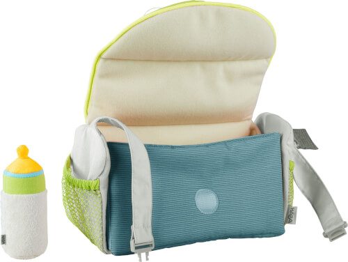 Auf dem Bild ist eine geöffnete Wickeltasche in Blau mit einem beigen Innenfutter zu sehen. Daneben steht eine kleine Babyflasche mit gelbem Deckel und grünem Rand.