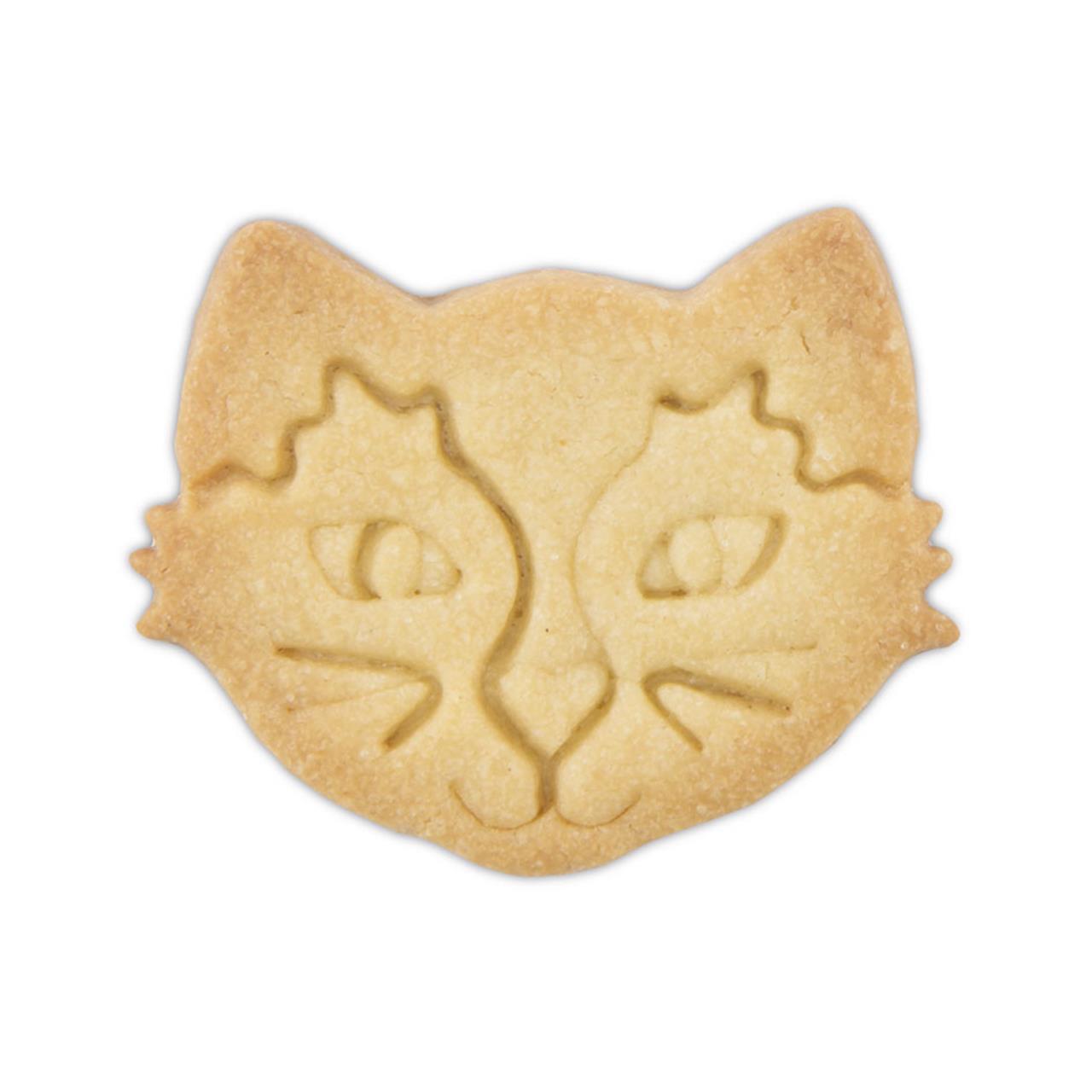 Das Bild zeigt einen Keks in Form eines Katzengesichts. Die Details wie Augen, Nase und Schnurrhaare sind in den Keks eingedrückt.