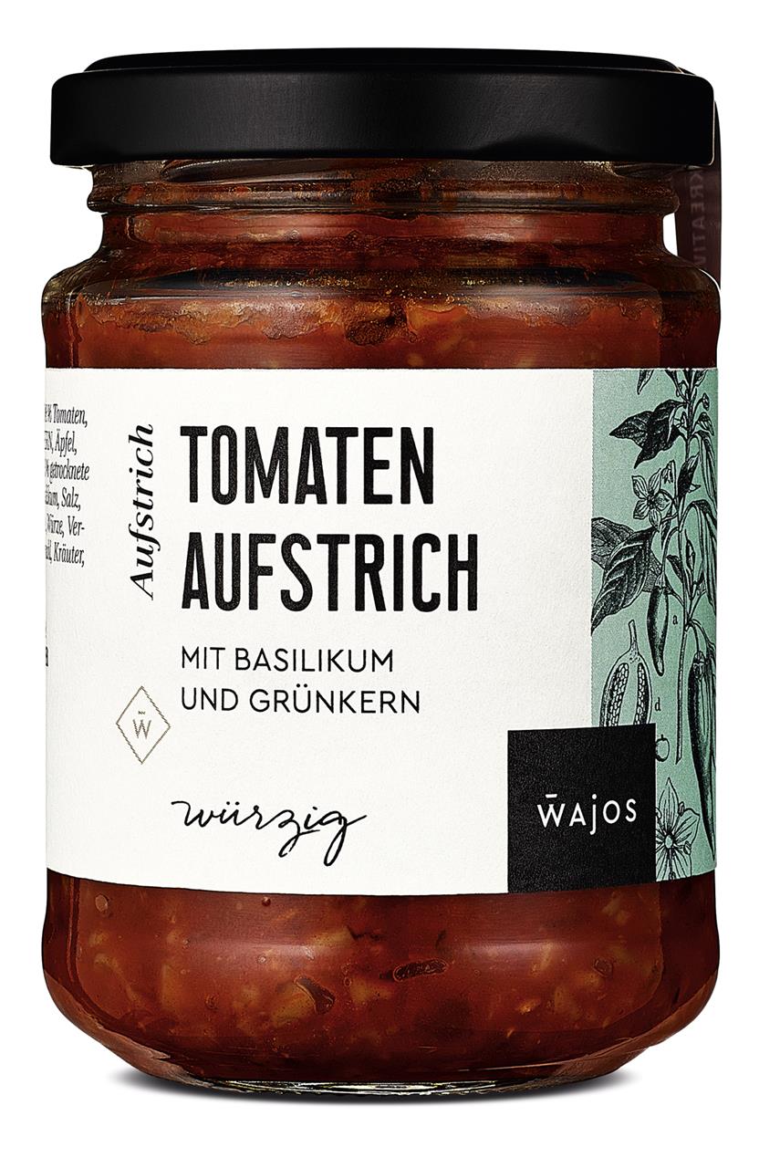 Das Bild zeigt ein Glas Tomaten Aufstrich mit Basilikum und Grünkern von der Marke Wajos. Das Glas enthält 185g eines würzigen Brotaufstrichs.