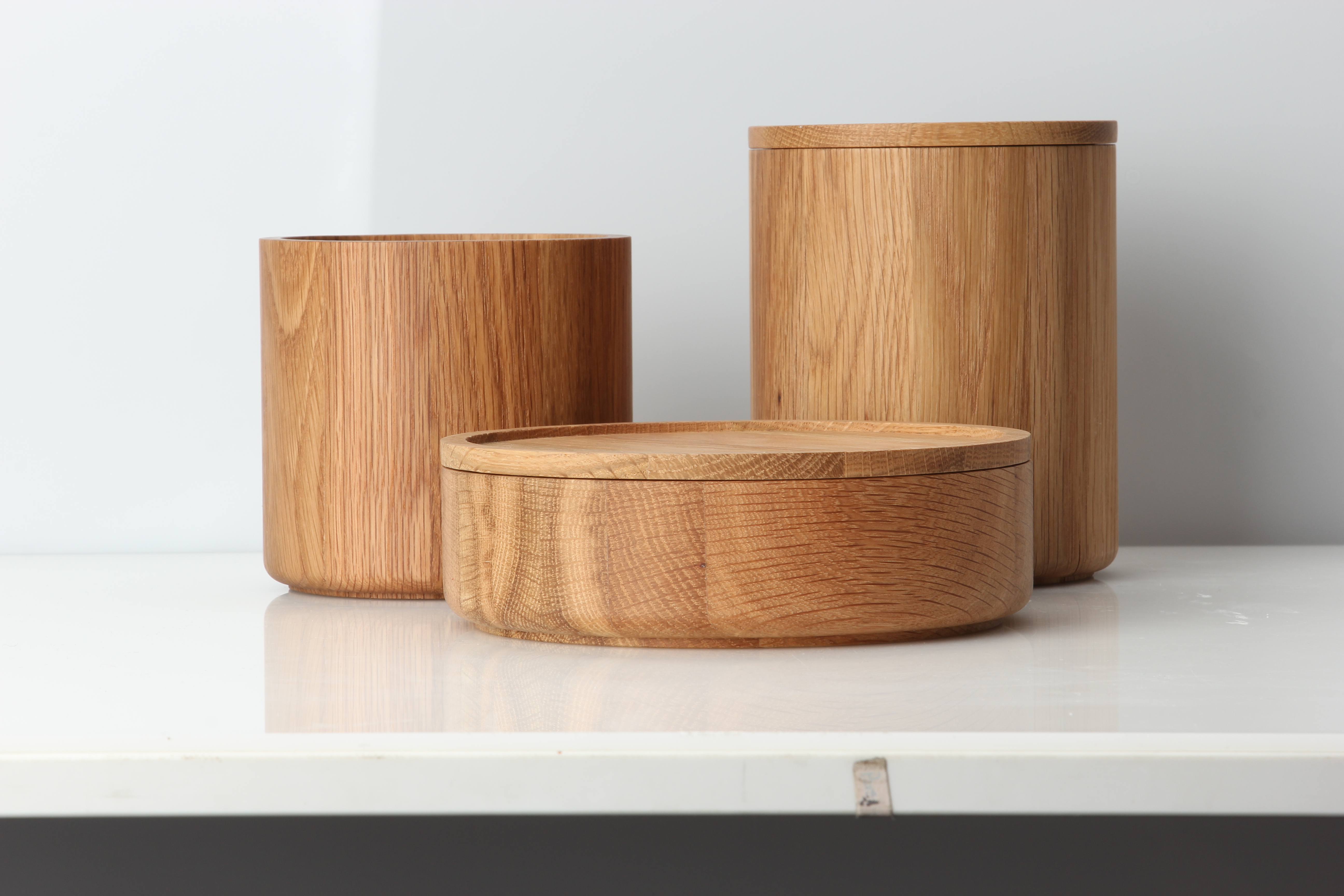 Auf dem Bild sind drei runde Holzgefäße in unterschiedlichen Größen zu sehen. Sie stehen auf einer weißen Oberfläche vor einem neutralen Hintergrund.