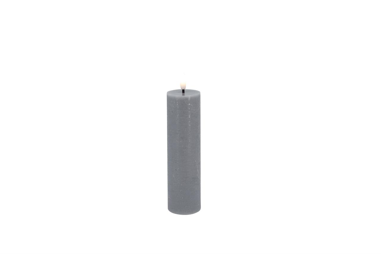 Auf dem Bild ist eine schlanke, graue LED-Stumpenkerze mit rustikaler Oberfläche zu sehen. Die Kerze leuchtet in einem warmweißen Ton.