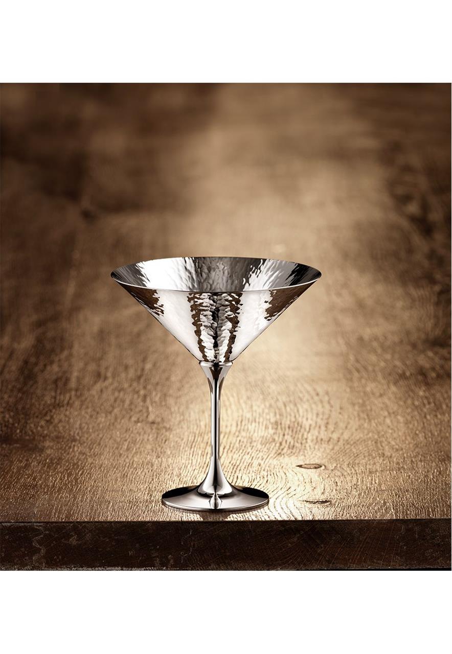 Das Bild zeigt die Martelé 90 Cocktailschale auf einem Holztisch. Das elegante Glas hat eine gehämmerte Metalloberfläche und reflektiert das Licht.