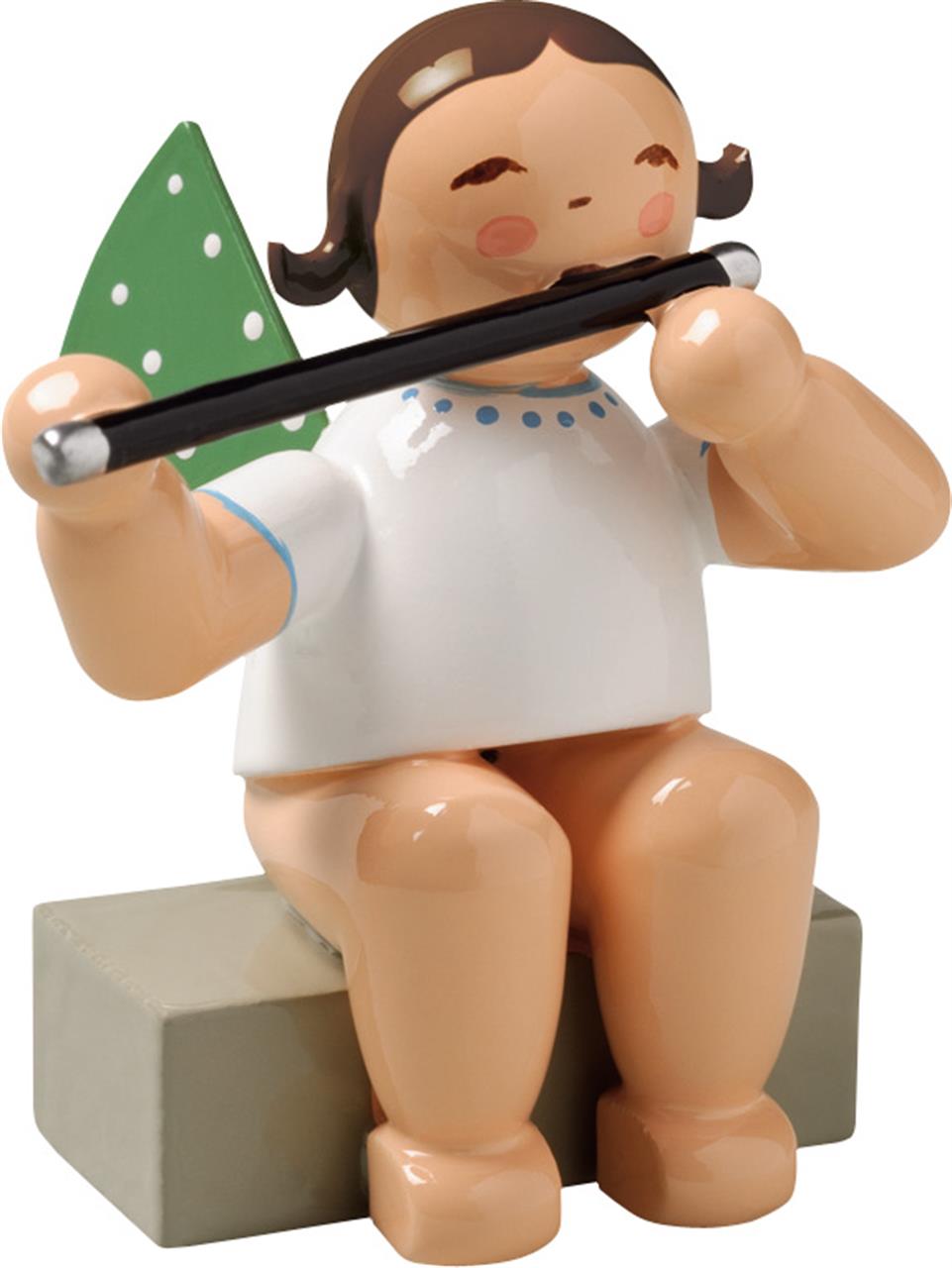 Die Figur zeigt einen sitzenden Engel mit grünen Flügeln und weißen Punkten. Der Engel spielt eine Querflöte und trägt ein weißes Kleid.