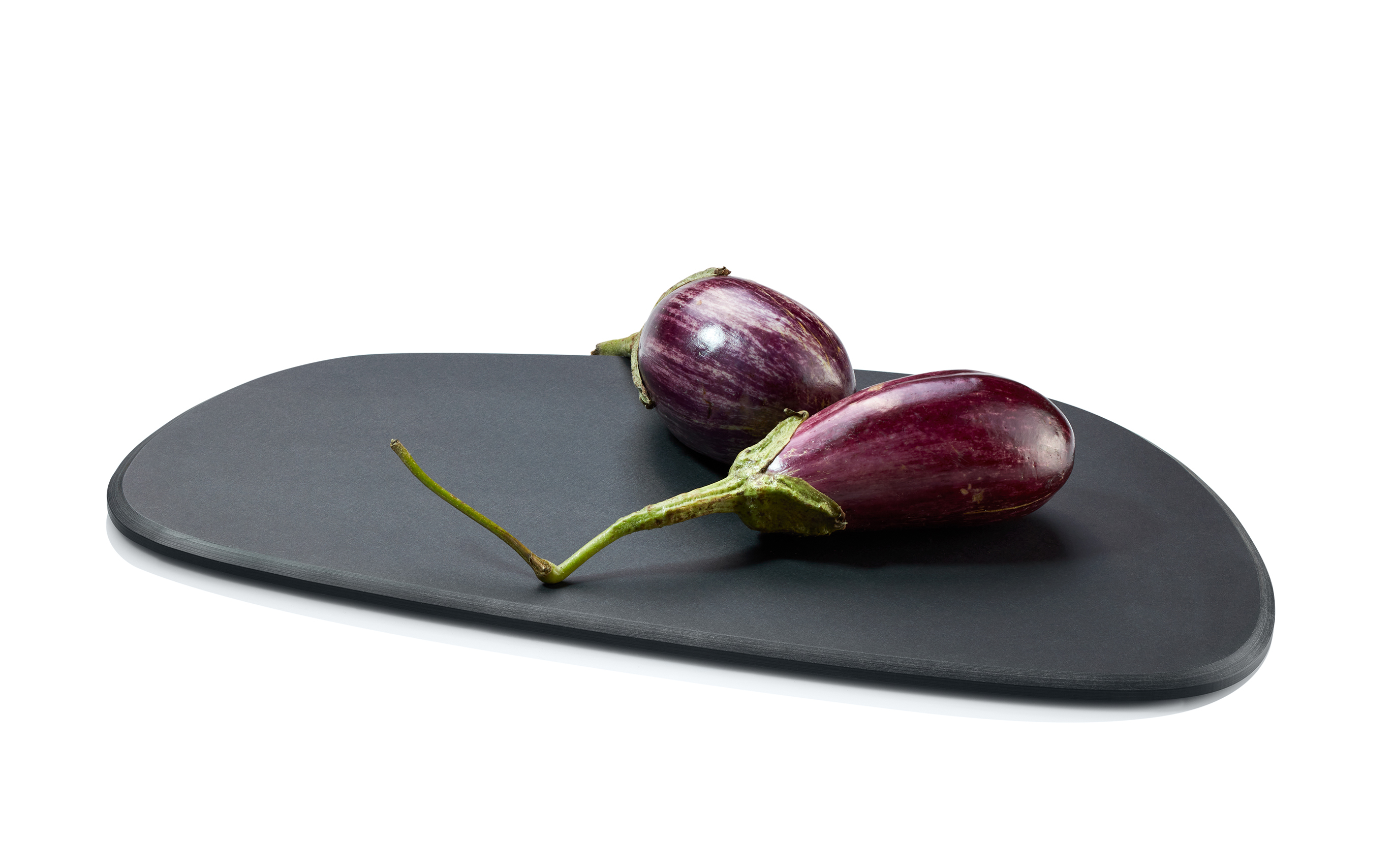 Auf dem Bild liegen zwei Auberginen auf einem schwarzen Schneidebrett. Der Hintergrund ist weiß und schlicht gehalten.