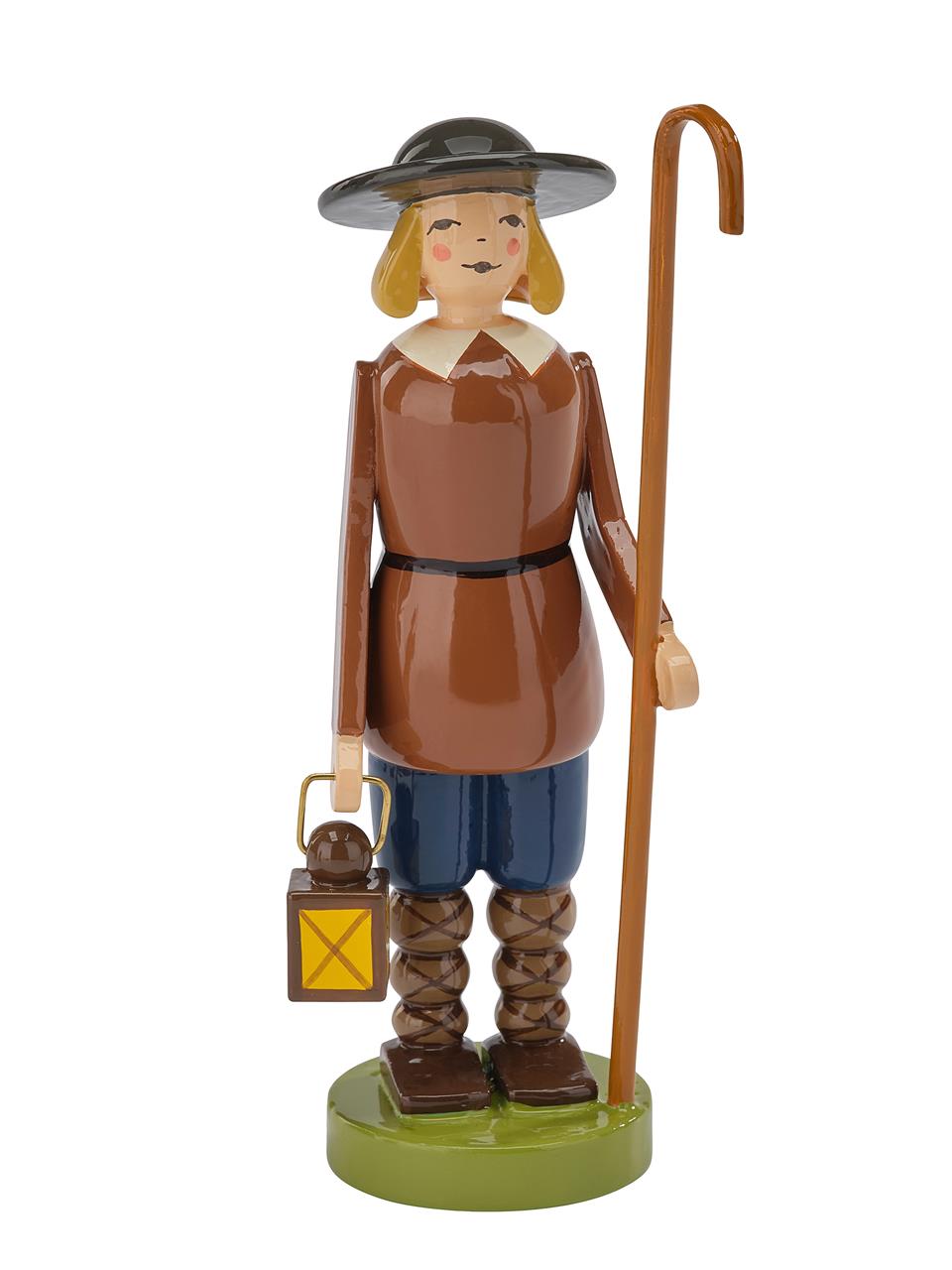 Die Figur zeigt einen Hirten mit Laterne und Hirtenstab. Er trägt braune Kleidung, einen schwarzen Hut und steht auf einem grünen Sockel.