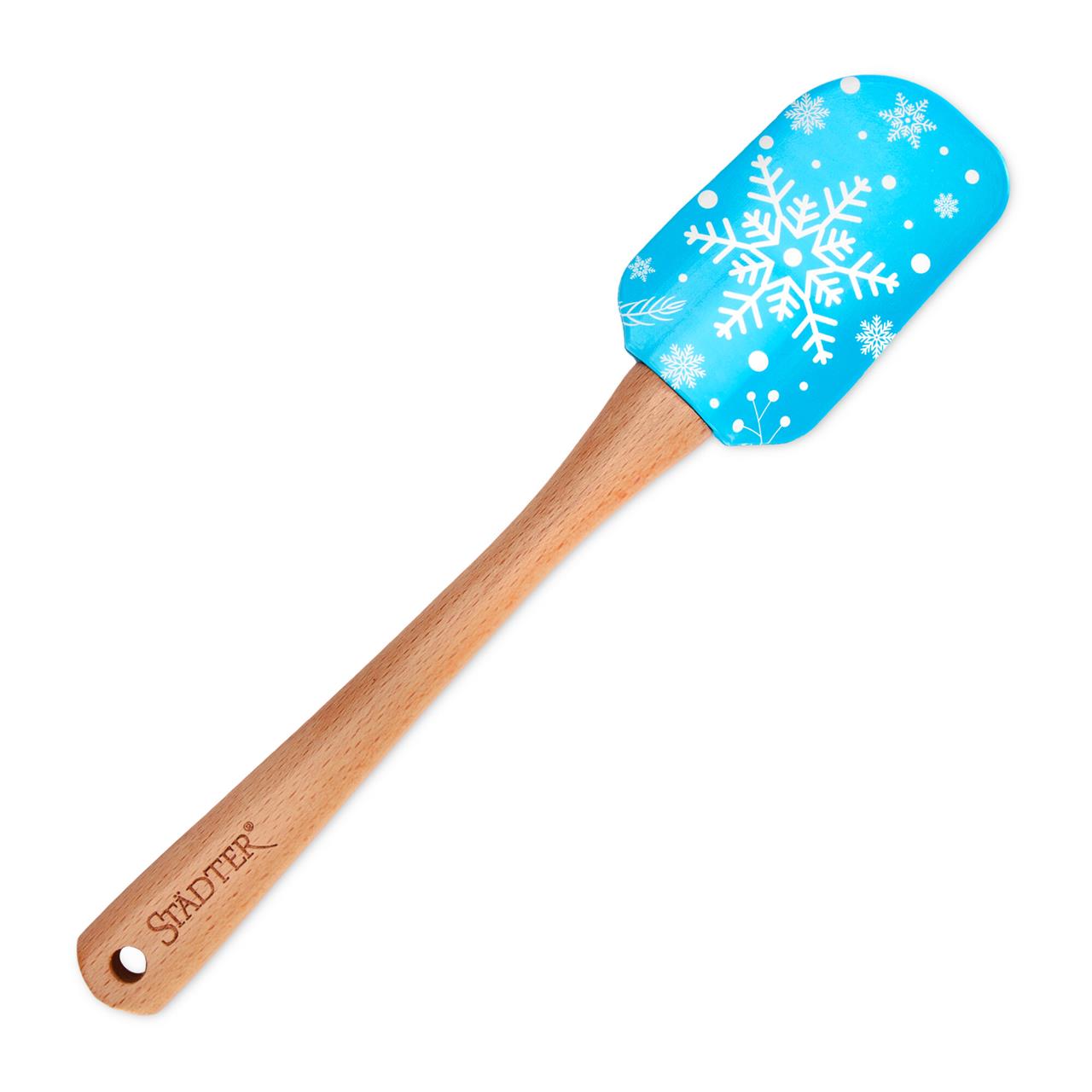 Das Bild zeigt einen Teigschaber mit einem Holzgriff und einem blauen, winterlich bedruckten Silikonkopf. Auf dem Silikonkopf sind weiße Schneeflocken abgebildet.