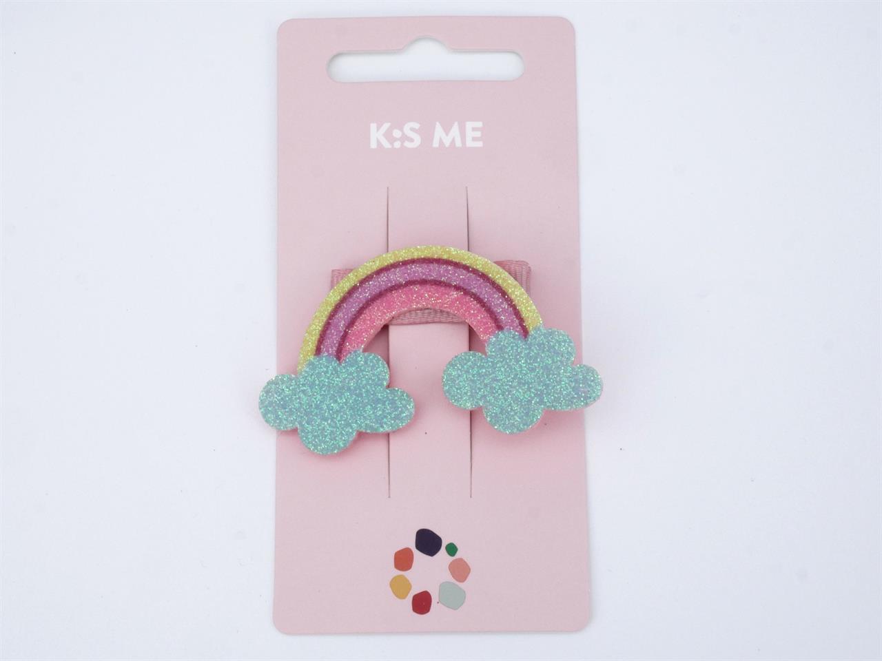 Das Bild zeigt eine glitzernde Haarspange in Form eines Regenbogens mit zwei blauen Wolken. Die Haarspange ist auf einer rosa Karte mit der Aufschrift "K:S ME" befestigt.