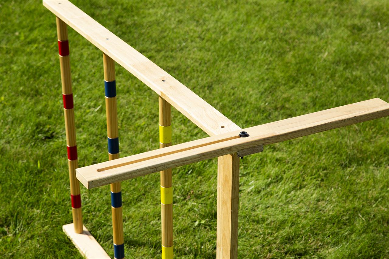 Das Bild zeigt das Spiel „Spin Ladder Original – Leitergolf“ aus Holz auf einer Wiese. Die Holzstäbe sind farbig markiert und das Spiel ist für den Outdoor-Gebrauch geeignet.