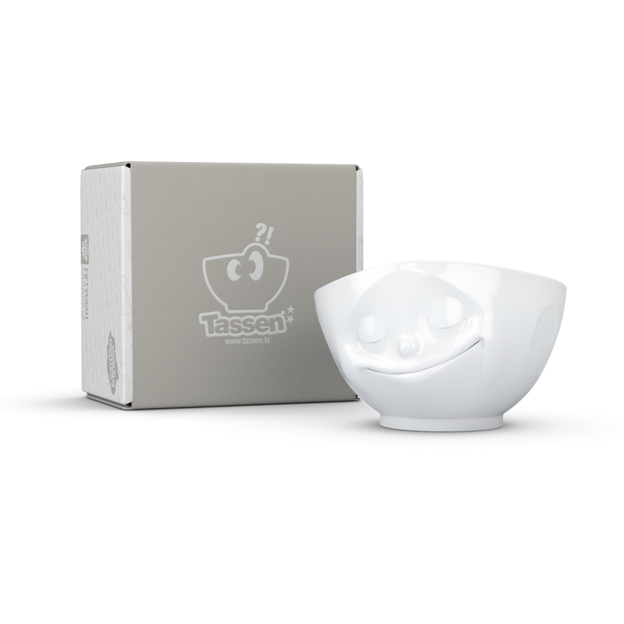 Die Abbildung zeigt eine weiße Schale mit einem fröhlichen Gesichtsausdruck und einem Fassungsvermögen von 500 ml. Neben der Schale steht eine Verpackung mit dem Markenlogo "Tassen".