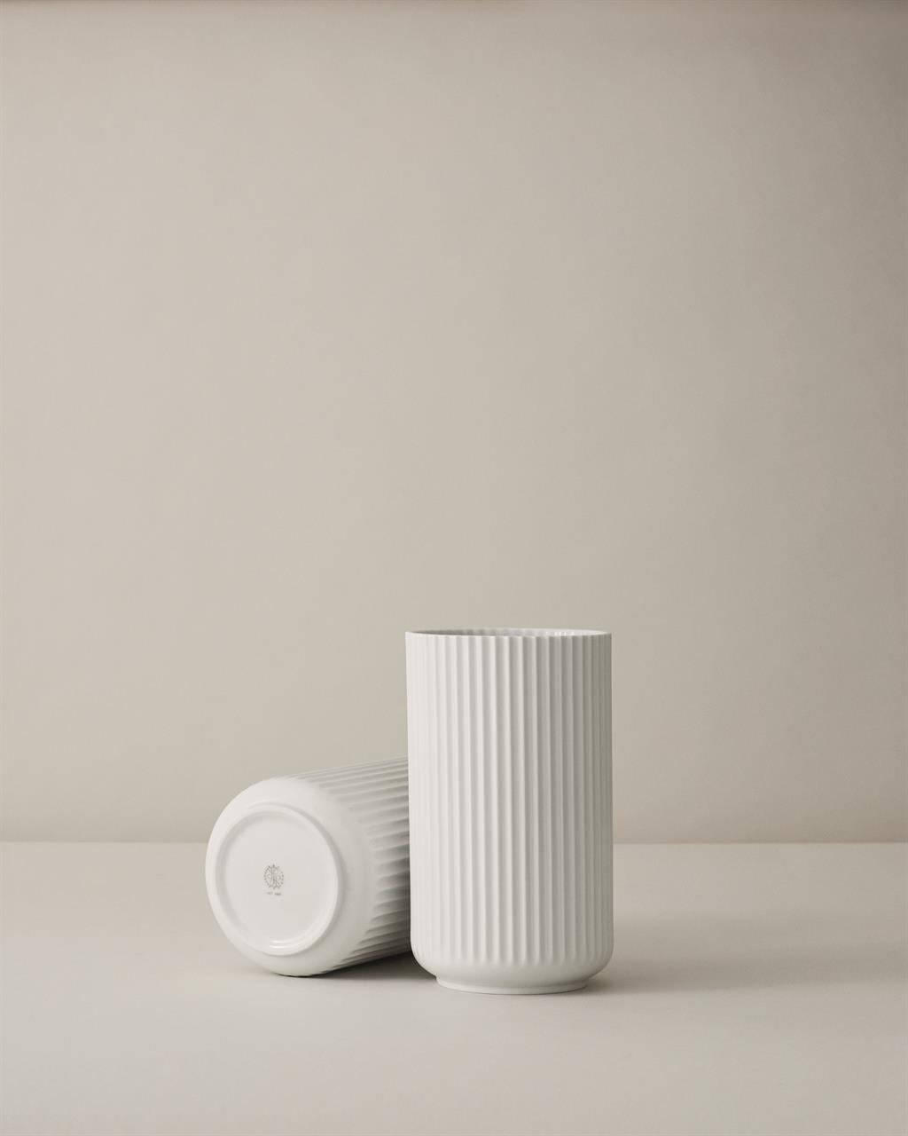 Auf dem Bild sind zwei Lyngby Vasen in Weiß, glänzend, zu sehen. Eine Vase steht aufrecht, während die andere seitlich liegt.