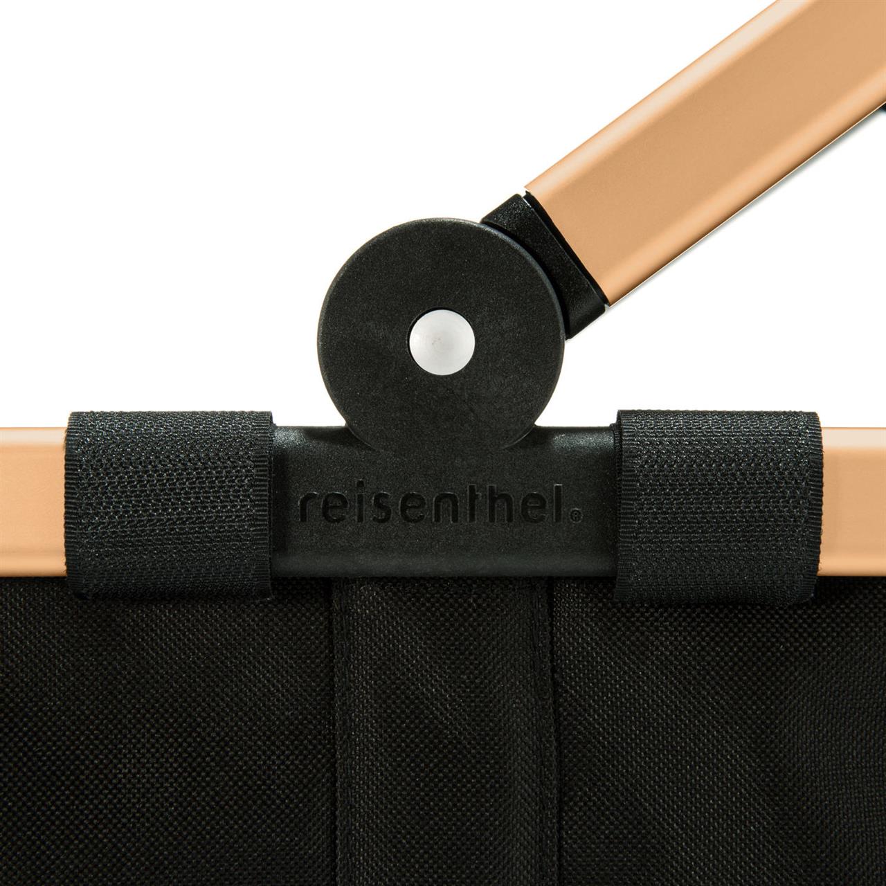 Das Bild zeigt einen Ausschnitt des Carrybag frame gold/black Einkaufskorbs von reisenthel. Zu sehen sind der goldene Rahmen, schwarze Stoff und ein Scharnier.