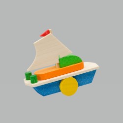 Das Bild zeigt ein buntes Holzsegelboot namens „Baumbehang Segelschiff“. Das Segelschiff ist schlicht gestaltet und hat eine weiße Segelfläche sowie blaue, grüne, orange und gelbe Elemente.