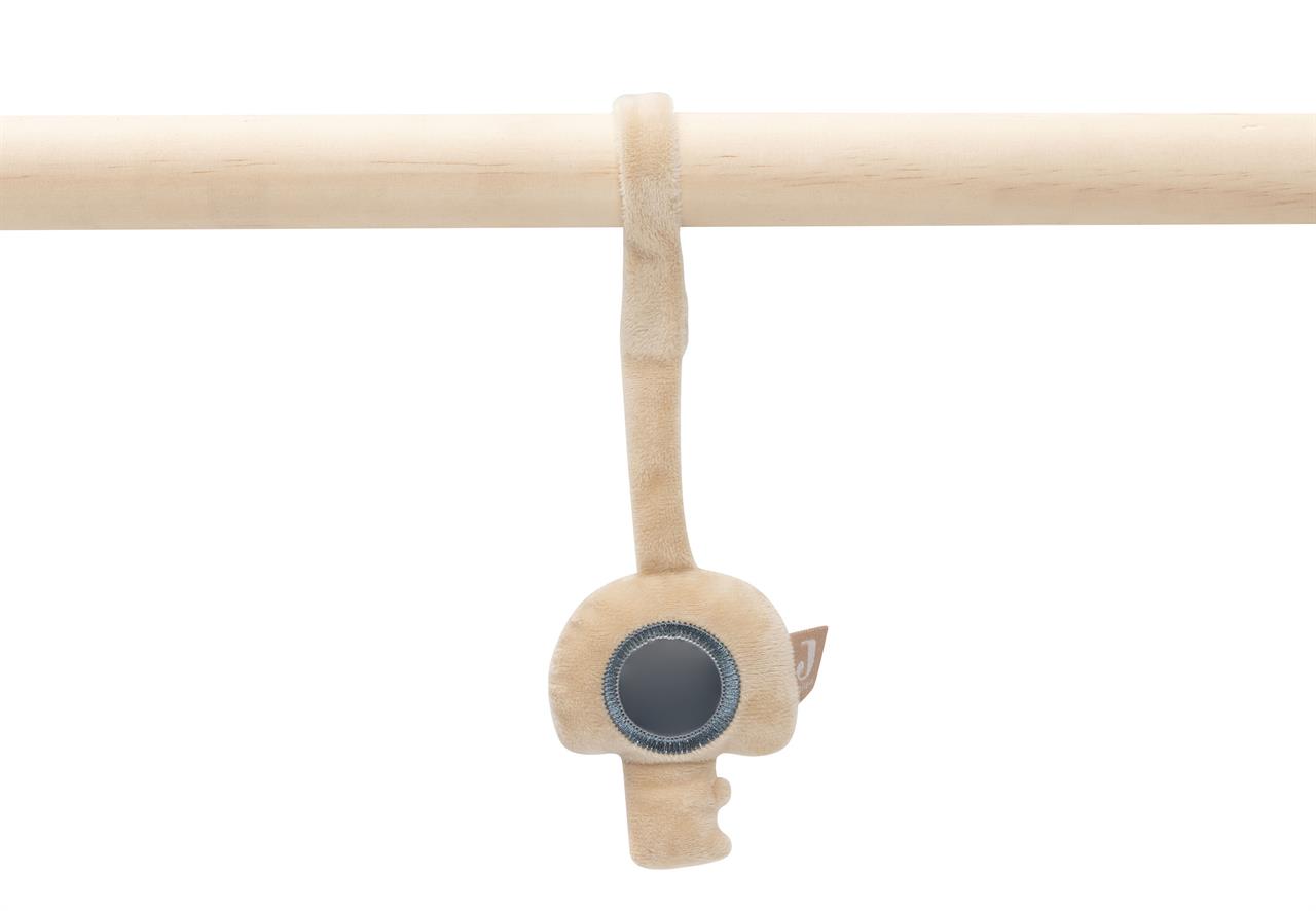 Das Bild zeigt ein beigefarbenes Babyspielzeug in Schlüssel-Form, das an einer Holzstange befestigt ist. In der Mitte des Spielzeugs befindet sich ein kleiner Spiegel.