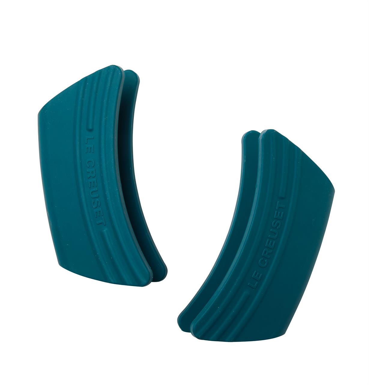 Das Bild zeigt ein zweiteiliges Set aus Silikon-Griffschutz in der Farbe Deep Teal. Die Schutzhüllen sind gebogen und tragen die Prägung "Le Creuset".