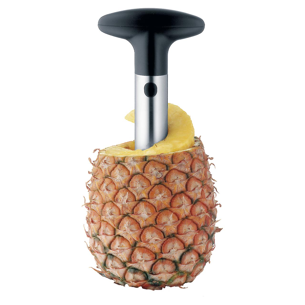 Das Bild zeigt einen Ananasschneider, der in eine frische Ananas gesteckt ist. Mit diesem Gerät kann man die Ananas einfach und sauber aus der Schale schneiden.
