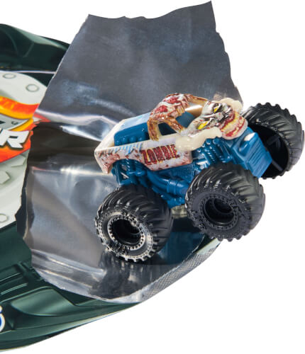 Auf dem Bild ist ein kleines Spielzeug-Monstertruck zu sehen. Der Truck fährt gerade aus einer silbernen Verpackung heraus.