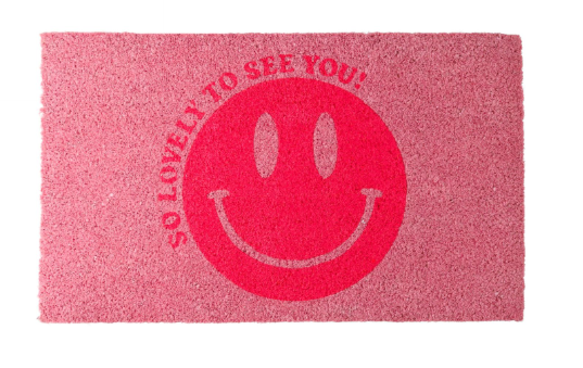 Zu sehen ist eine Fussmatte mit dem Motiv 'So lovely to see you' und einem lachenden Design. Diese Matte begrüßt den Besucher freundlich.