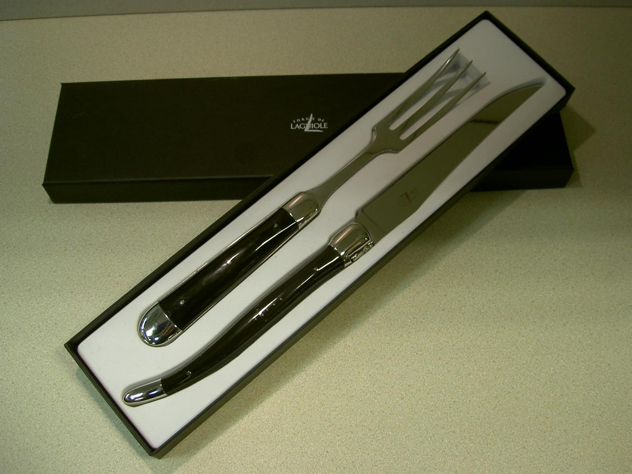 Das Bild zeigt ein Tranchierbesteck-Set mit zwei Besteckteilen und dunklen Horngriffen. Das Set ist elegant in einer Geschenkbox präsentiert.