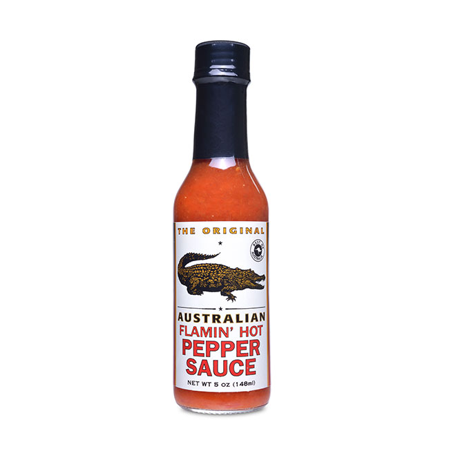 Auf dem Bild ist eine Flasche „Australian Flamin' Hot Pepper Sauce“ mit 148 ml Inhalt zu sehen. Die Flasche hat ein Etikett mit einem Krokodil und roter Schrift.