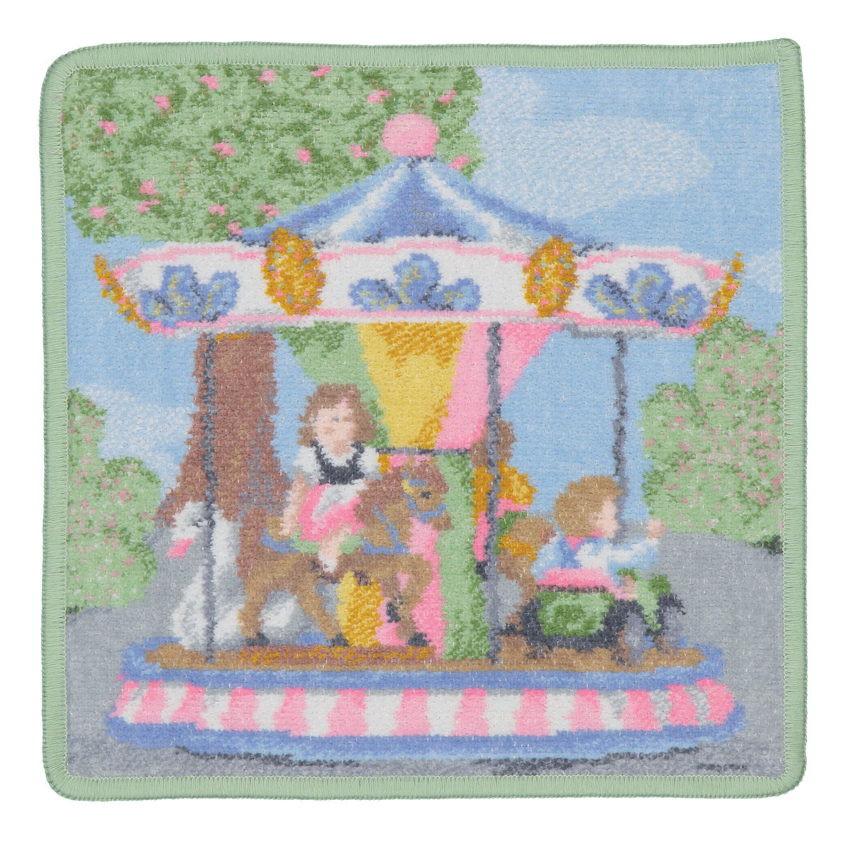 Das Bild zeigt das Produkt "Seiftuch Funfair 25x25" mit einem bunten Motiv eines Karussells. Auf dem Karussell sind Kinder und ein Hund zu sehen, umgeben von Bäumen und einem blauen Himmel.