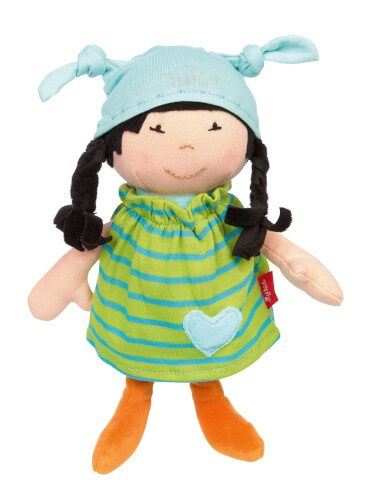 Auf dem Bild ist eine Stoffpuppe mit schwarzen Zöpfen und einem blauen Mützchen zu sehen. Sie trägt ein grünes Kleid mit blauen Streifen und einem blauen Herz, sowie orangefarbene Schuhe.