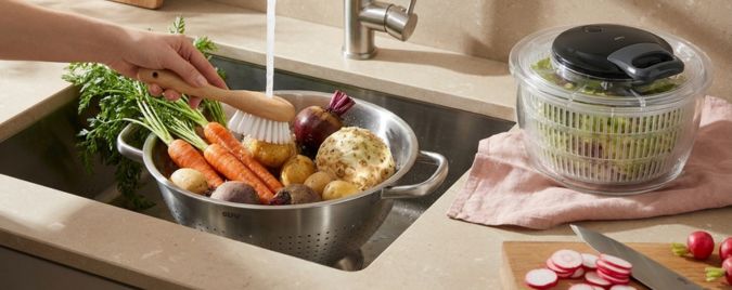 Das Bild zeigt Siebe und eine Salatschleuder. Diese Küchenutensilien werden beim Kochen und Zubereiten von Salaten benutzt.