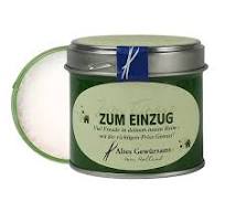 Die Abbildung zeigt eine grüne Geschenkdose mit der Aufschrift "Zum Einzug" und enthält 80g Sonnensalzflocken. Der Deckel der Dose ist leicht geöffnet und das Salz ist sichtbar.