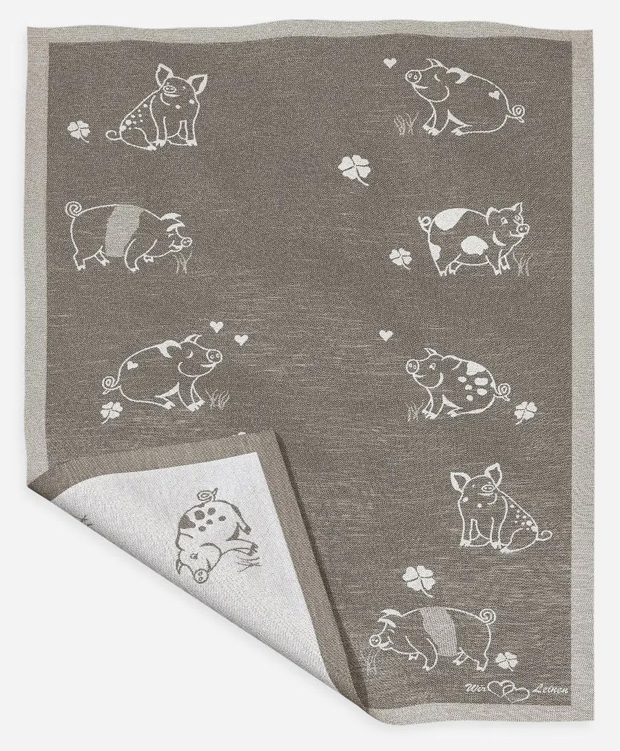 Das Bild zeigt ein braunes Halbleinen-Geschirrtuch mit dem Namen "Eberhart", das 45x73 cm groß ist. Auf dem Tuch sind verschiedene weiße Schweinchen und Kleeblätter abgebildet.