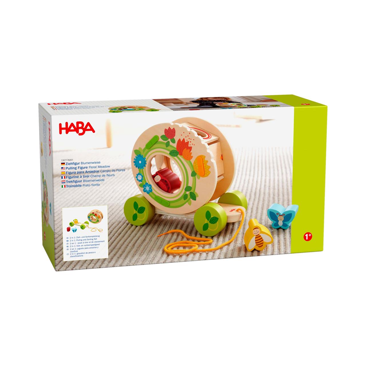 Das Bild zeigt die Verpackung des Produkts "Ziehfigur Blumenwiese" von HABA. Es handelt sich um ein buntes Holzspielzeug zum Ziehen, das für Kinder ab 1 Jahr geeignet ist.