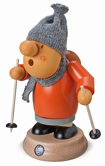 Die Figur zeigt einen Holzräuchermann im Winteroutfit mit roter Jacke, Schal und Mütze. Er hält zwei Skistöcke in den Händen und steht auf einem Holzsockel.