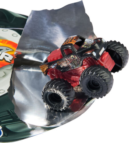 Auf dem Bild ist ein kleines Spielzeug-Monstertruck zu sehen. Das Auto befindet sich auf einer aufgerissenen Verpackung aus silberner Folie.