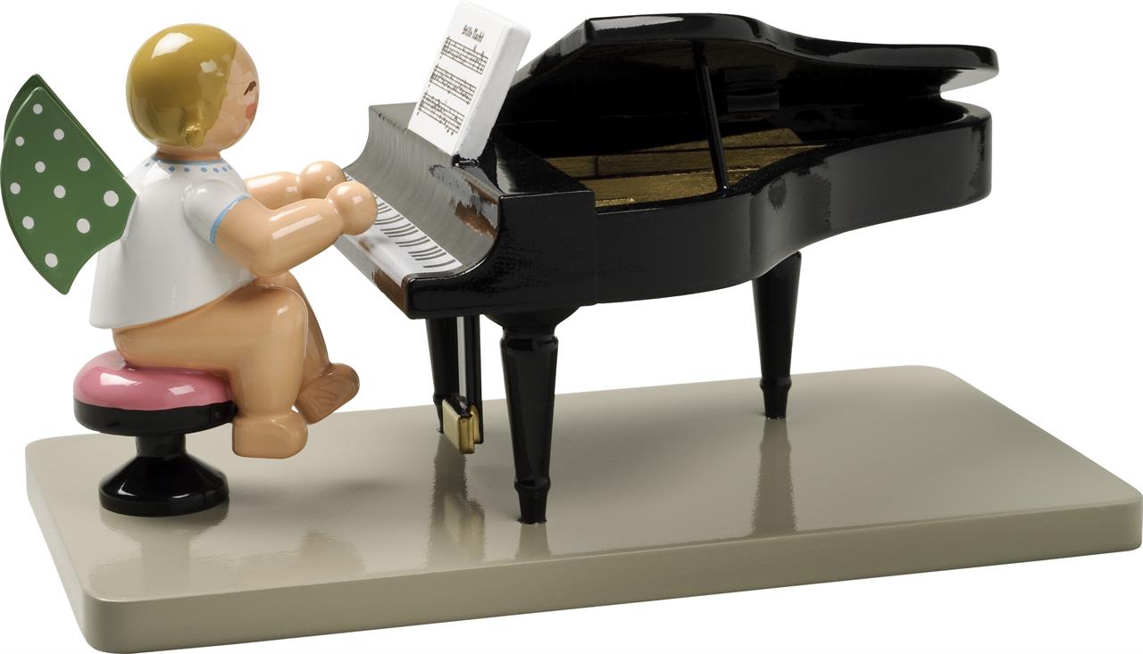 Das Bild zeigt eine kleine Engelsfigur mit grünen Flügeln, die an einem schwarzen Flügel sitzt und Klavier spielt. Die Figur sitzt auf einem pinken Hocker und vor ihr steht ein Notenblatt auf dem Klavier.