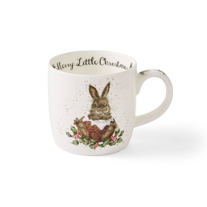 Auf der Tasse ist ein fröhlicher Hase mit einem Weihnachtskuchen und Stechpalmenblättern abgebildet. Am Rand der Tasse steht der Schriftzug „Merry Little Christmas“.