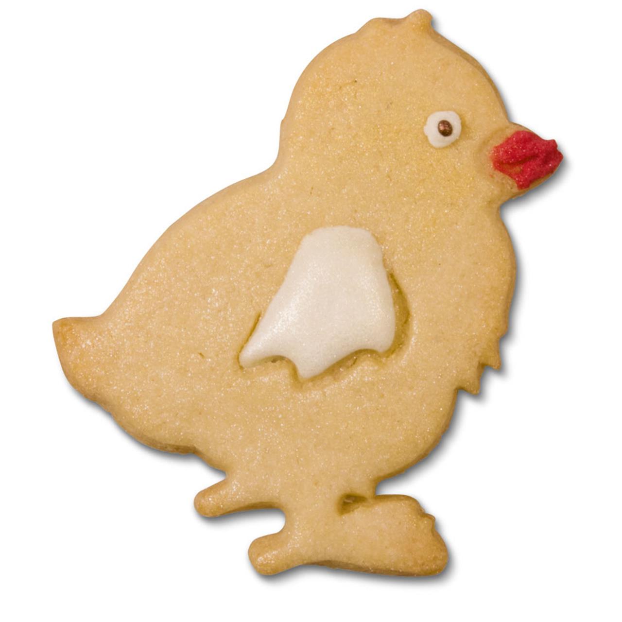 Das Bild zeigt einen Keks in Form eines Kükens. Der Keks ist mit einem weißen Flügel und einem roten Schnabel verziert.