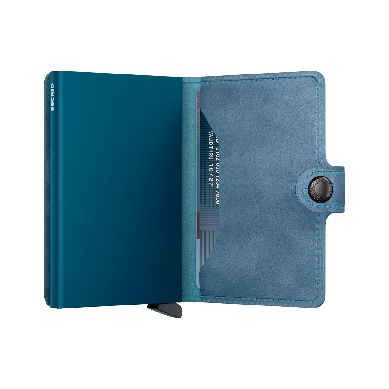 Das Bild zeigt das Produkt "Miniwallet Vintage Teal", ein kompaktes Portemonnaie in Blautönen. Es ist geöffnet und enthält mehrere Kartenfächer sowie einen Druckknopfverschluss.