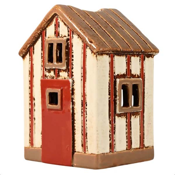 Das Bild zeigt ein kleines Strandhaus aus Keramik in Creme und Rot. Es ist als Teelichthalter gestaltet und hat Fenster und eine Tür.