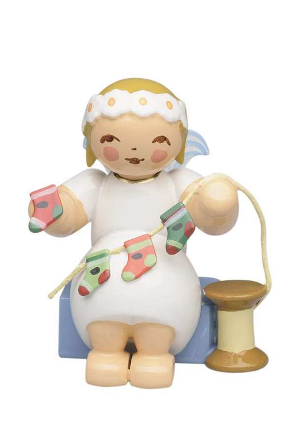 Auf dem Bild ist ein sitzender Margeritenengel mit einem Adventskalender zu sehen. Die Figur wirkt detailreich und festlich gestaltet.