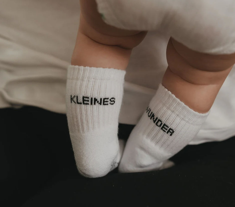 Babysocken mit der Aufschrift 'Kleines Wunder' in Größe 16-18 sind abgebildet. Die Socken sind für Babys geeignet.